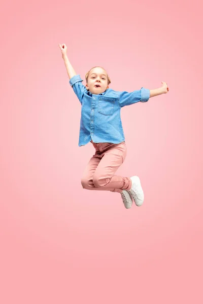 Young happy caucasian teen girl jumping in the air, isolated on pink studio background. — Stock Photo, Image