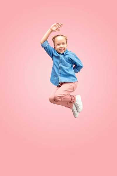 Genç mutlu beyaz genç kız pembe studio arka plan üzerinde izole havada atlama. — Stok fotoğraf