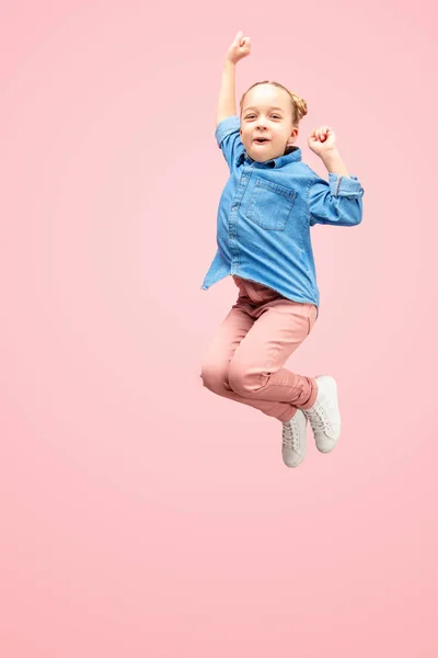 Gelukkig Kaukasische tiener meisje springen in de lucht, geïsoleerd op roze studio achtergrond. — Stockfoto