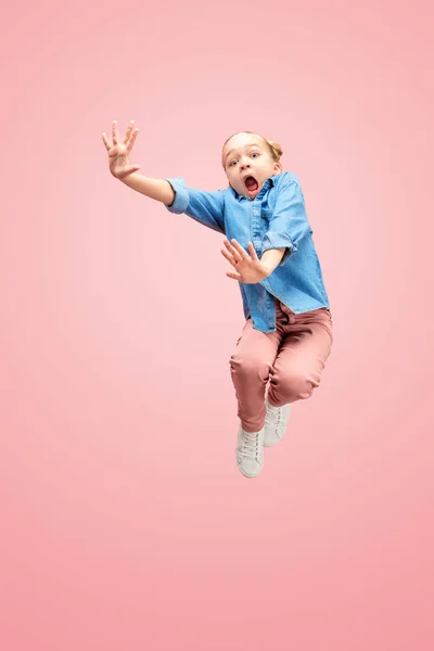Jovem assustado caucasiano adolescente menina pulando no ar, isolado no fundo do estúdio rosa . — Fotografia de Stock