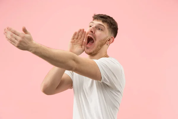 Изолированный на розовый молодой случайный мужчина кричит в студии — стоковое фото