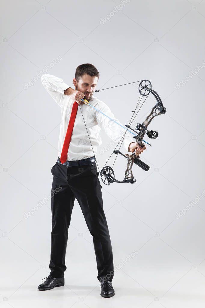 Businessman aiming at target with bow and arrow, isolated on white background