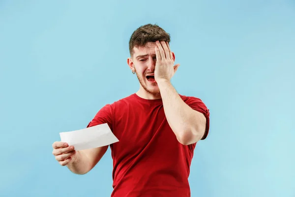 Jovem com uma expressão surpresa aposta deslizamento no fundo azul — Fotografia de Stock