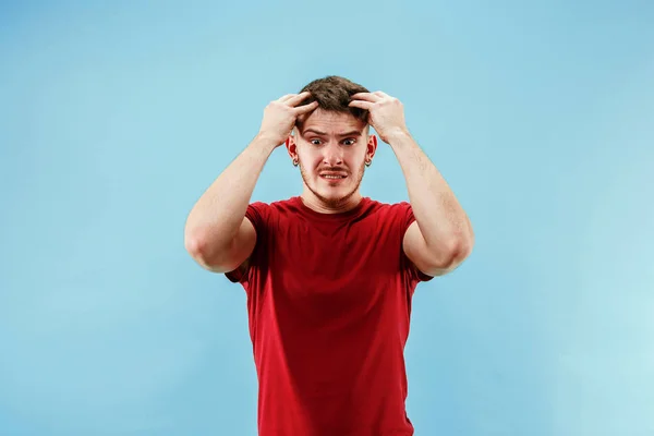 Jovem com uma expressão surpresa aposta deslizamento no fundo azul — Fotografia de Stock