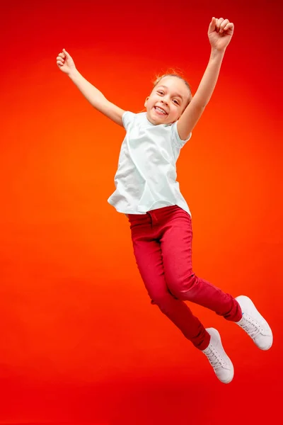 Ευτυχισμένος Καυκάσιος έφηβος κοπέλα πηδώντας στον αέρα, απομονώνονται σε φόντο κόκκινο στούντιο. — Φωτογραφία Αρχείου