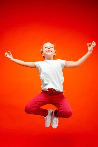 Young happy caucasian teen girl jumping in the air, isolated on red studio background. — Stock Photo, Image