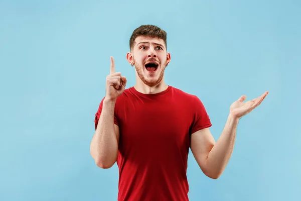 De jonge, aantrekkelijke man op zoek verrast geïsoleerd op blauw — Stockfoto