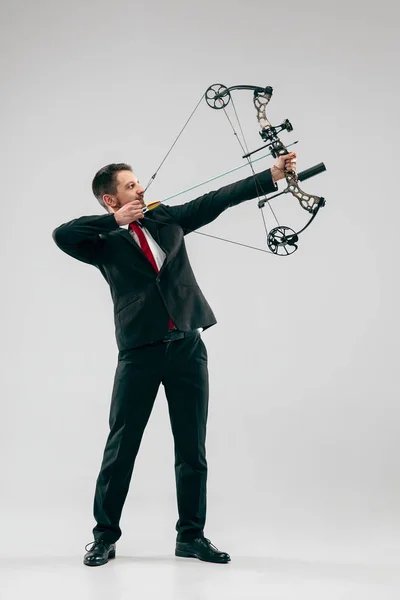 Uomo d'affari che mira al bersaglio con arco e freccia, isolato su sfondo bianco — Foto Stock