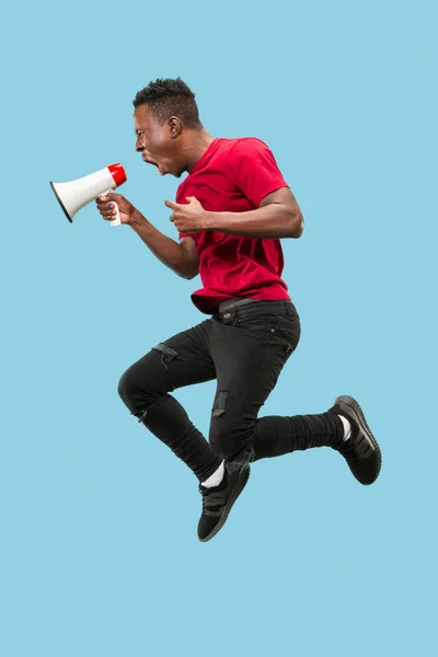 Abanico de fútbol saltando sobre fondo azul. El joven afro hombre como aficionado al fútbol con megáfono — Foto de Stock