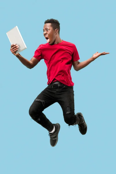 노트북을 사용 하 여 노란색 배경 위에 절연 점프 행복 흥분된 젊은 아프리카 남자의 이미지 — 스톡 사진