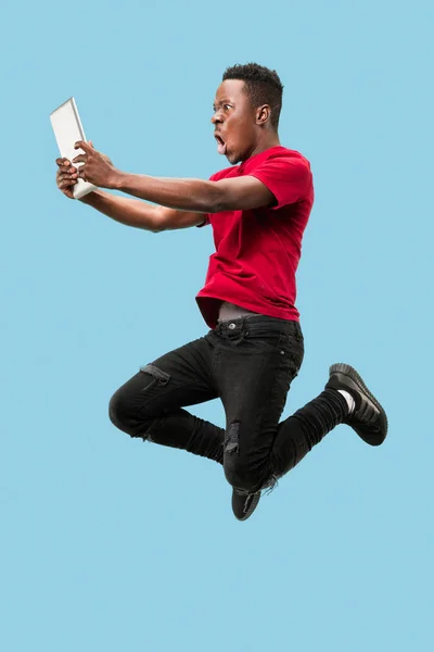 Imagen de un joven africano feliz y excitado saltando aislado sobre un fondo amarillo usando una computadora portátil — Foto de Stock