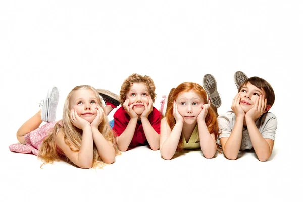 Gros plan d'enfants heureux allongés sur le sol en studio et regardant vers le haut, isolés sur fond blanc — Photo