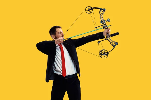 Бізнесмен, спрямований на ціль з луком і стрілою, ізольований на жовтому тлі — стокове фото