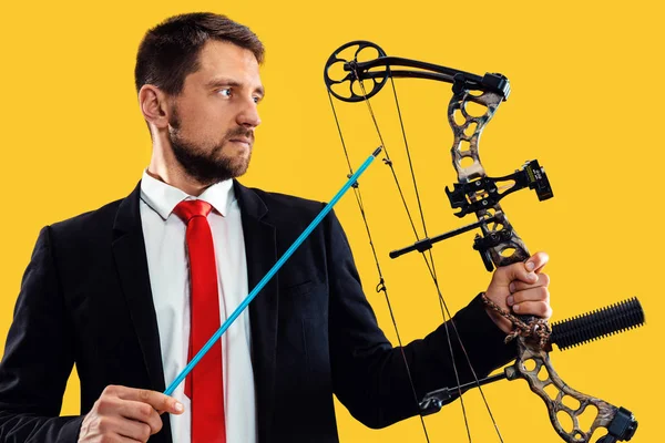 Businessman aiming at target with bow and arrow, isolated on yellow background — Stock Photo, Image