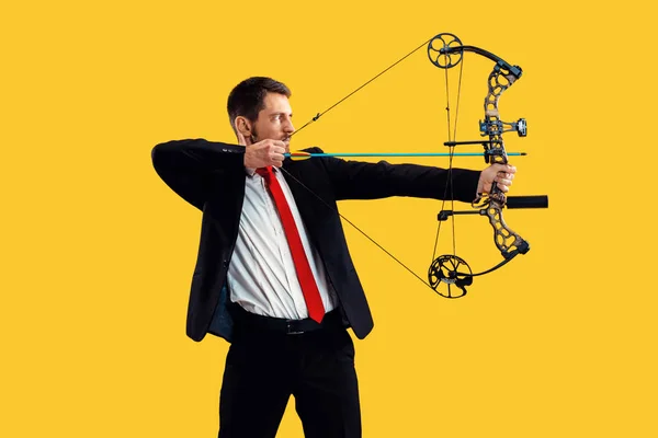 Бізнесмен, спрямований на ціль з луком і стрілою, ізольований на жовтому тлі — стокове фото