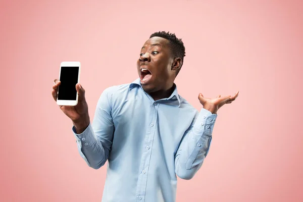 Retrato interior de atractivo joven negro sosteniendo teléfono inteligente en blanco — Foto de Stock