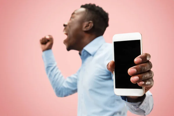Крытый портрет привлекательного молодого чернокожего мужчины с пустым смартфоном — стоковое фото
