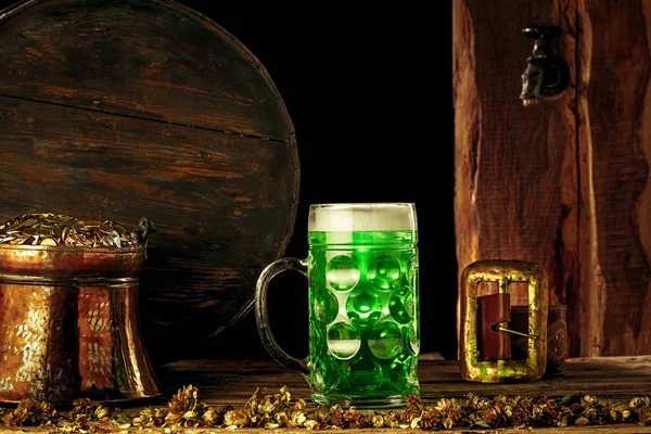 Дерев'яний фон з великою кількістю золотих монет і великою чашкою пива з зеленим бантом . — стокове фото