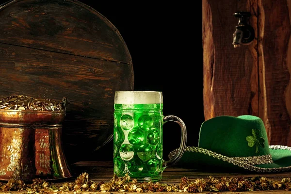 Дерев'яний фон з великою кількістю золотих монет і великою чашкою пива з зеленим бантом . — стокове фото