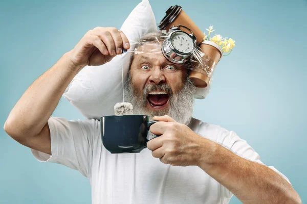 Hombre cansado durmiendo en casa con demasiado trabajo. Empresario aburrido con almohada y reloj de arena — Foto de Stock