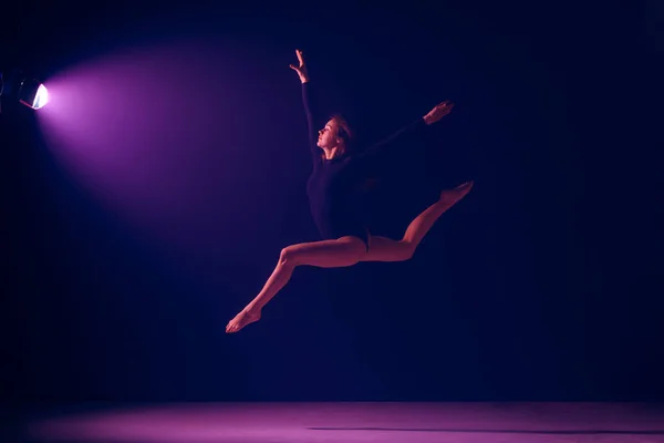 Unga kvinnliga balettdansös på neonljus studio bakgrund. — Stockfoto