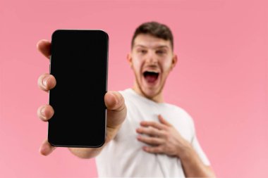 Yakışıklı delikanlı smartphone ekran şok sürpriz yüzü olan pembe arka plan üzerinde izole gösterilen