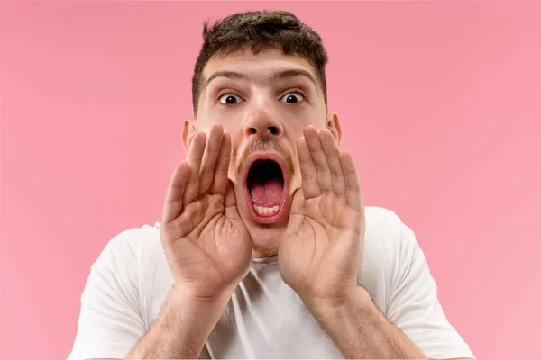 Na białym tle na różowy młody człowiek dorywczo, krzycząc w studio — Zdjęcie stockowe