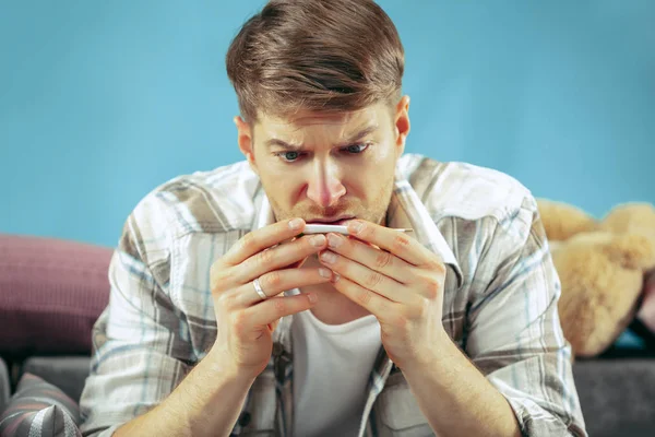 Homme barbu malade avec cheminée assis sur le canapé à la maison. Maladie, grippe, concept de douleur. Détente à la maison. Concepts des soins de santé . — Photo