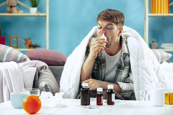 Vousatý muž nemocný komínu sedí na gauči doma. Onemocnění, chřipky, bolesti koncept. Odpočinek doma. Zdravotní pojmy. — Stock fotografie