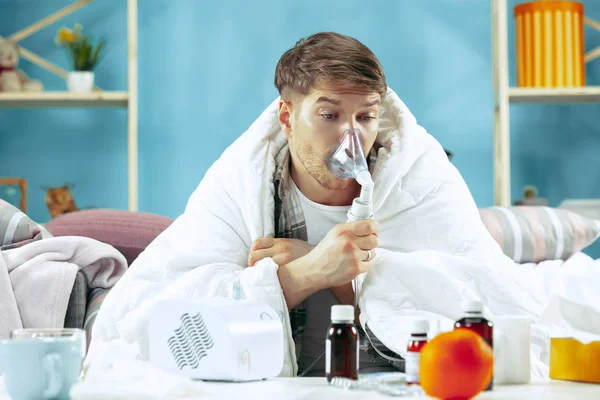 Hombre enfermo barbudo con chimenea sentado en el sofá en casa. Enfermedad, gripe, concepto de dolor. Relajación en casa. Conceptos sanitarios . —  Fotos de Stock