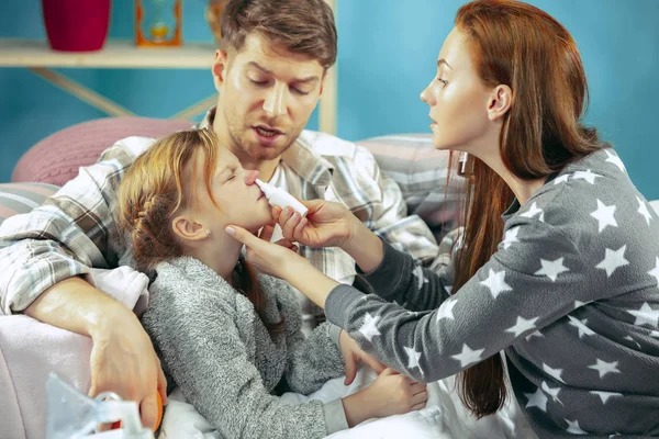 Os pais jovens com filha doente em casa. A família doente . — Fotografia de Stock