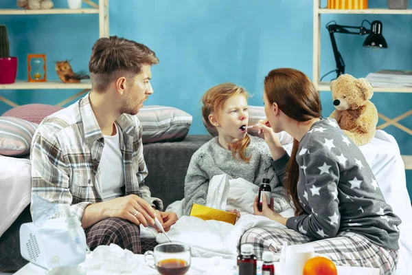 De jonge ouders met zieke dochter thuis. De zieke familie. — Stockfoto