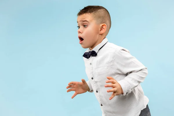 Der junge attraktive Teenie-Junge schaut überrascht isoliert auf blau — Stockfoto