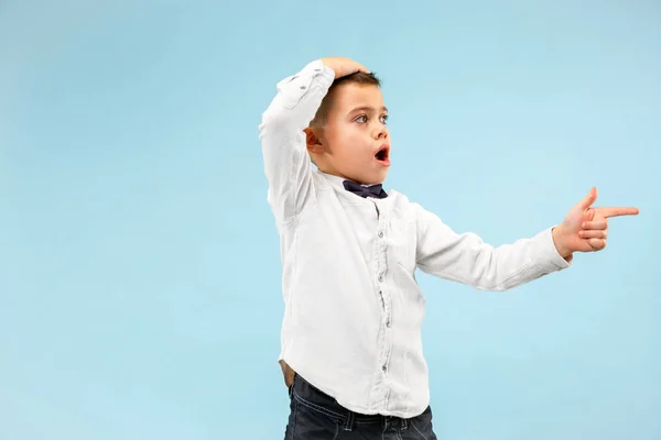 Der junge attraktive Teenie-Junge schaut überrascht isoliert auf blau — Stockfoto