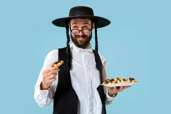 Purim Yahudi festivali için Hamantaschen kurabiyeyle siyah şapkalı genç Ortodoks Yahudi adam — Stok fotoğraf