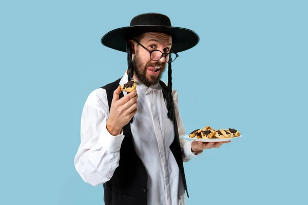 O homem judeu ortodoxo jovem com chapéu preto com biscoitos de Hamantaschen de festival judaico de Purim — Fotografia de Stock