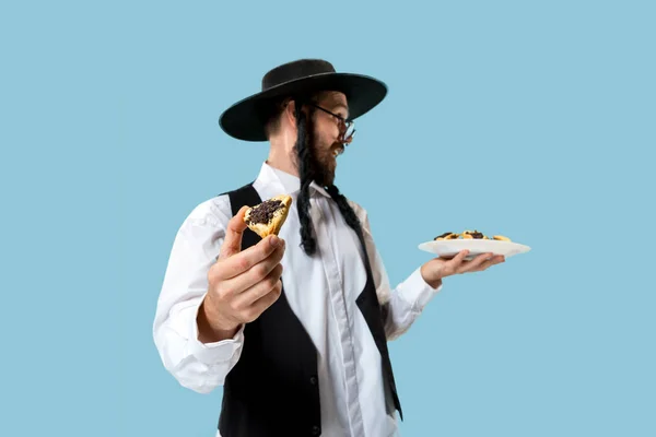 The young orthodox Jewish man with black hat with Hamantaschen cookies for Jewish festival of Purim