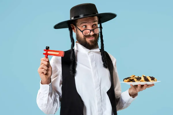 Purim Yahudi festivali için Hamantaschen kurabiyeyle siyah şapkalı genç Ortodoks Yahudi adam — Stok fotoğraf