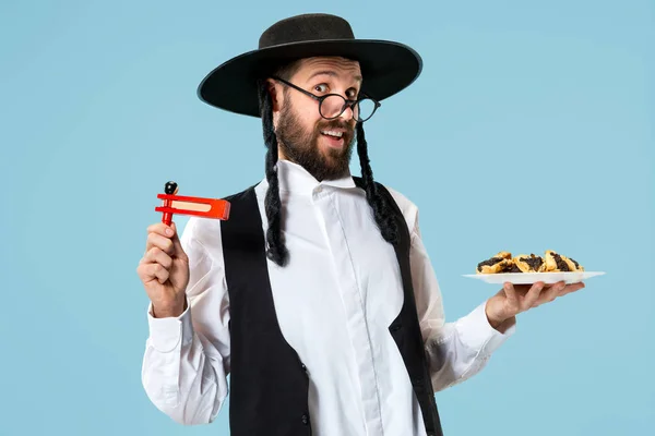 O homem judeu ortodoxo jovem com chapéu preto com biscoitos de Hamantaschen de festival judaico de Purim — Fotografia de Stock