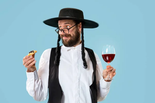 The young orthodox Jewish man with black hat with Hamantaschen cookies for Jewish festival of Purim