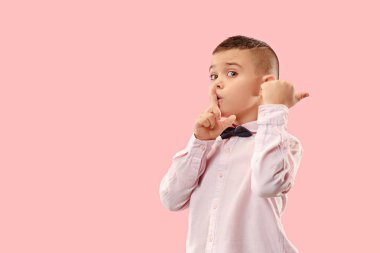 Pembe arka plan üzerinde elini arkasındaki sır fısıldayan genç çocuk