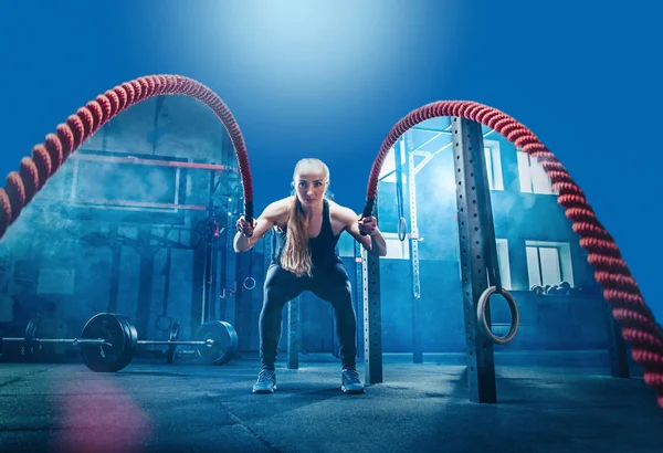 Mujer con cuerdas de batalla ejercitarse en el gimnasio de fitness . —  Fotos de Stock