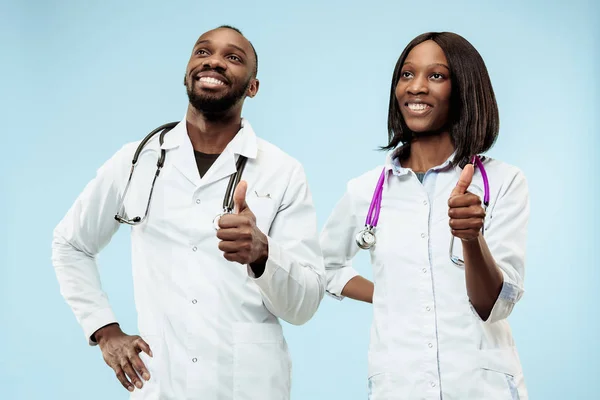 Los médicos afro-americanos felices femeninos y masculinos sobre fondo azul —  Fotos de Stock