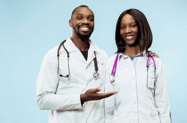 Los médicos afro-americanos felices femeninos y masculinos sobre fondo azul —  Fotos de Stock