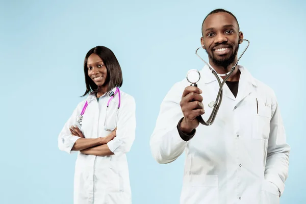 Kadın ve erkek mutlu afro Amerikan doktorlar mavi zemin üzerine — Stok fotoğraf
