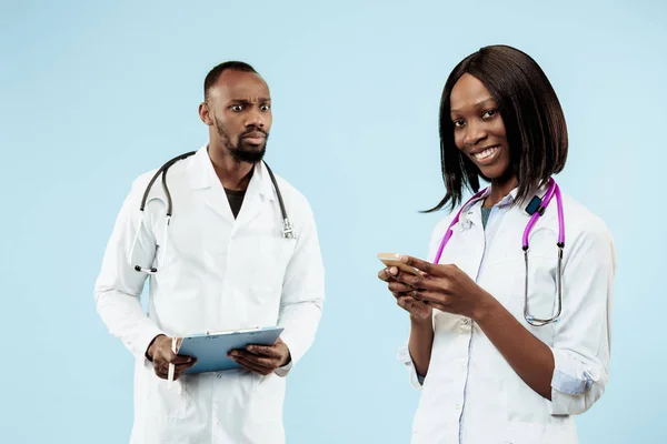 Los médicos afro-americanos felices femeninos y masculinos sobre fondo azul —  Fotos de Stock