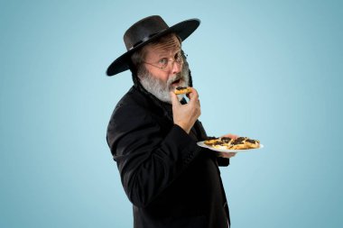 Purim Yahudi festivali için Hamantaschen kurabiyeyle siyah şapka ile üst düzey Ortodoks Yahudi adam