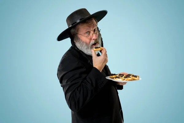 El hombre judío ortodoxo mayor con sombrero negro con galletas Hamantaschen para el festival judío de Purim — Foto de Stock