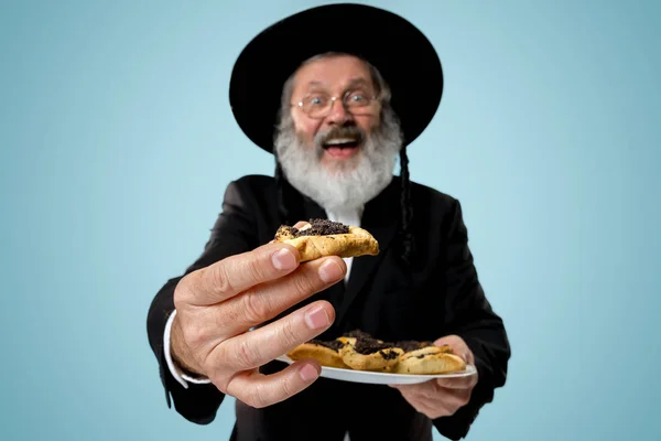 プリムのユダヤ人の祭りの Hamantaschen クッキーと黒い帽子の上級の正統派ユダヤ人の男 — ストック写真