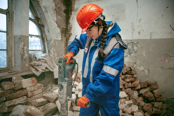 Жінка в шоломі використовує чоловічі робочі інструменти — стокове фото